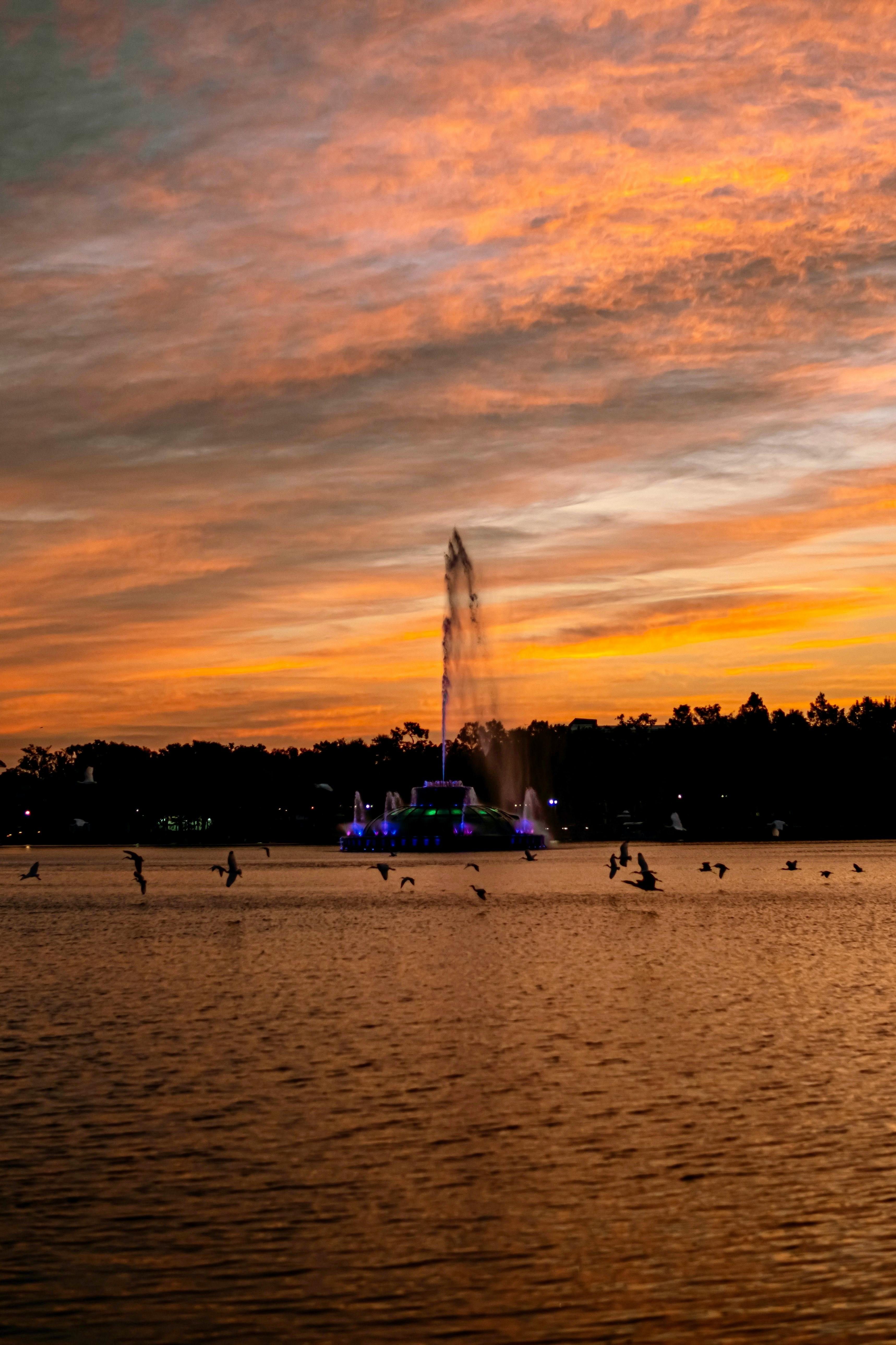 a sunset with a fountain in the middle of the water