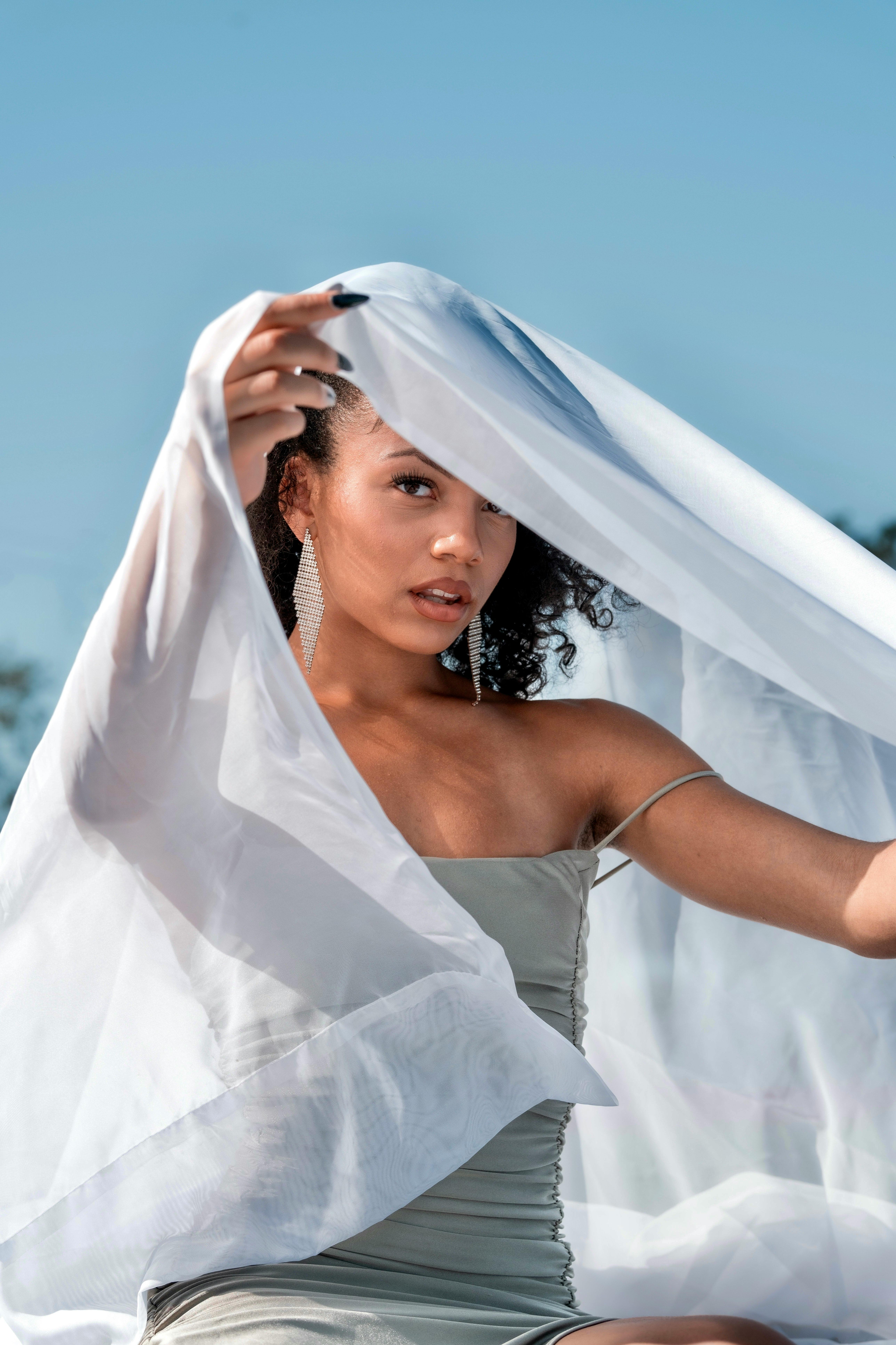 a woman in a white dress is holding a white sheet