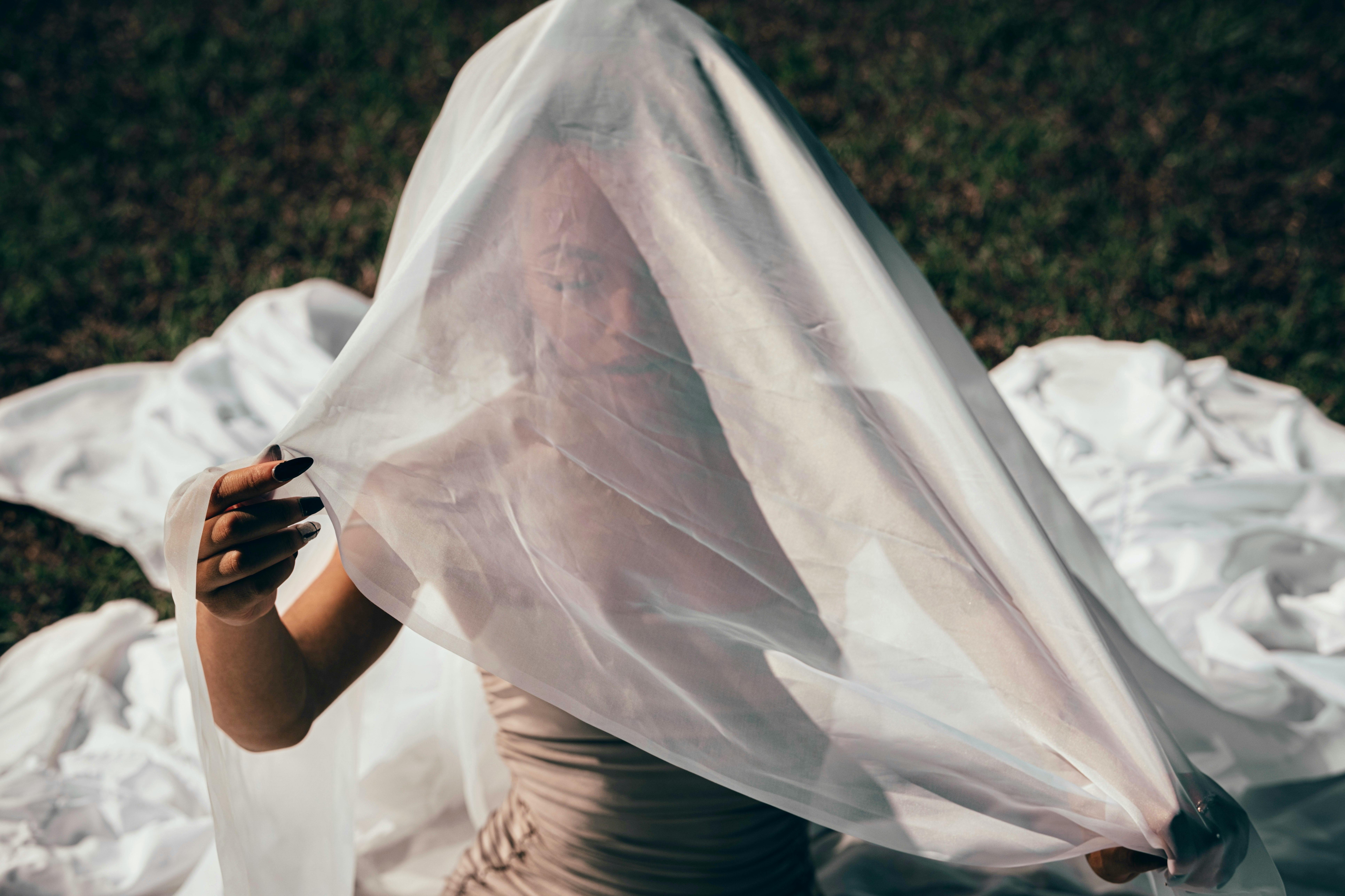 a woman is sitting on the ground with a veil over her head