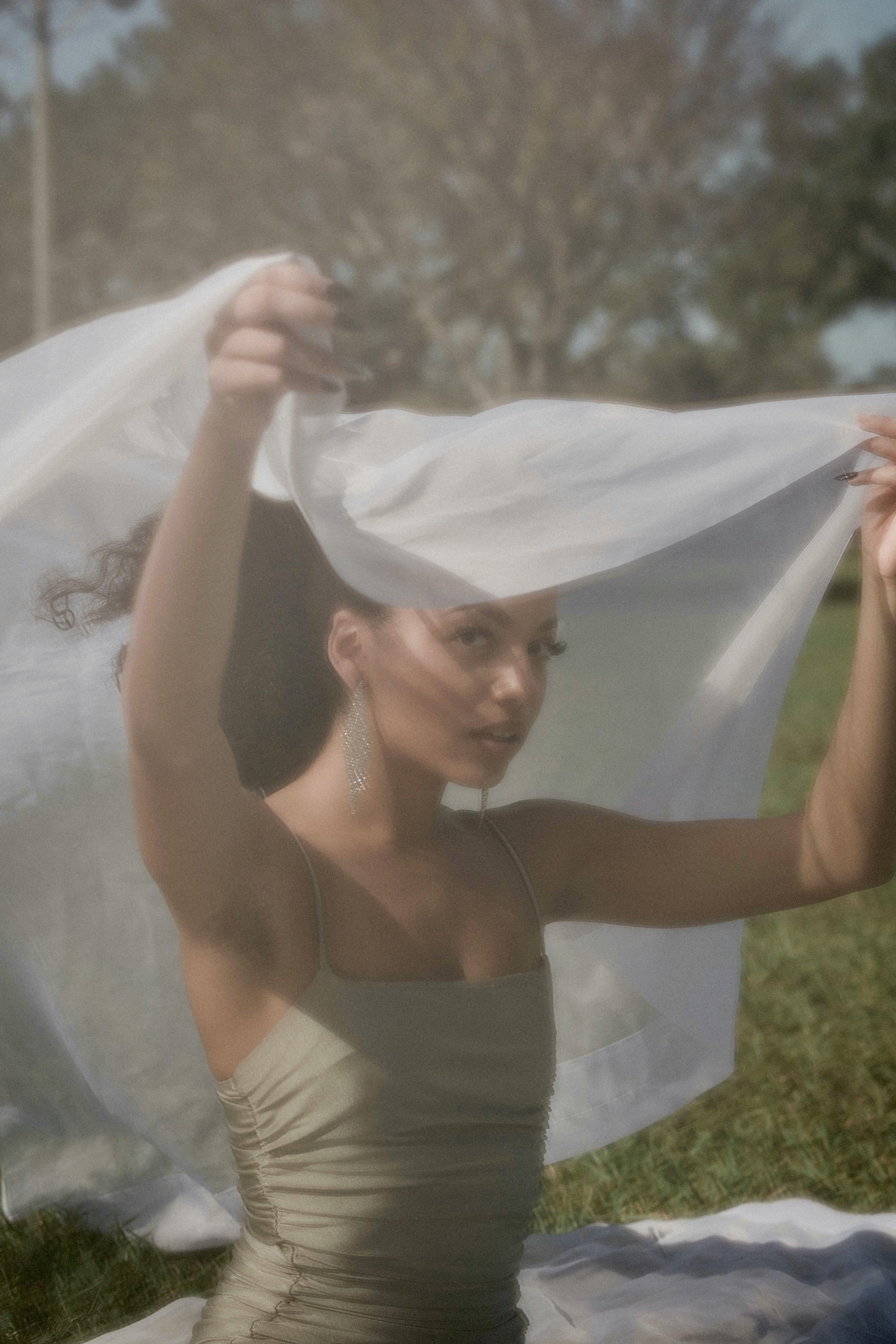 a woman in a white dress holding up a white sheet