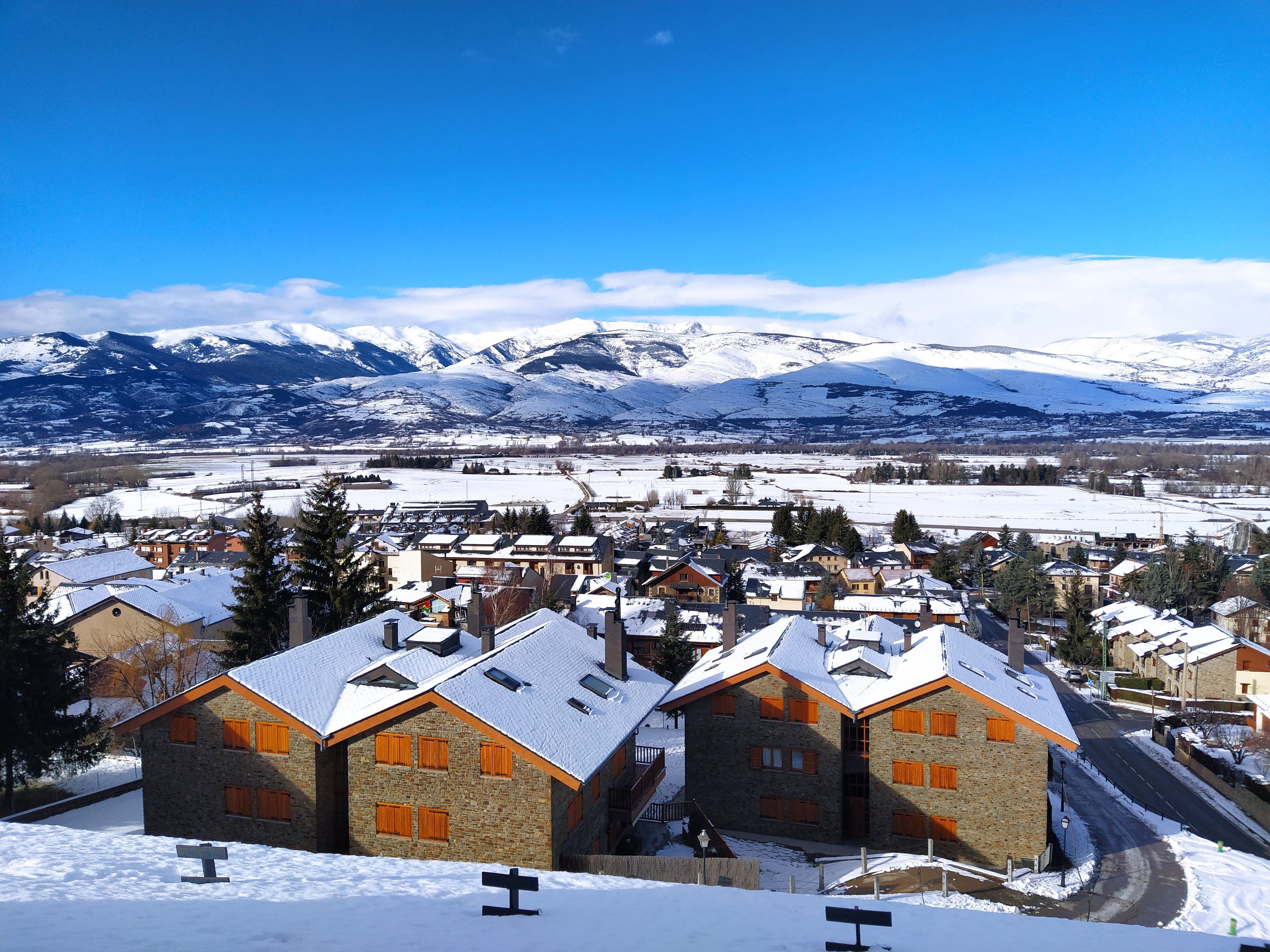 A picturesque town in winter surrounded by mountains with snow-covered roofs and landscapes.