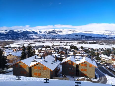 A picturesque town in winter surrounded by mountains with snow-covered roofs and landscapes.
