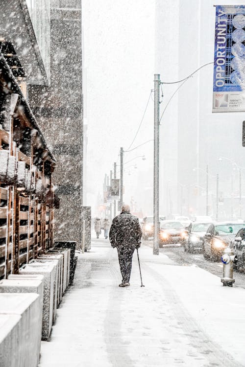 Man Walking on Sidewalk in Snowfall