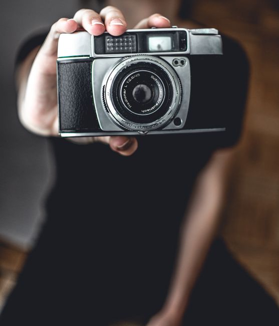 Close-up photo of a person holding a vintage camera, displaying intricate details and classic design.