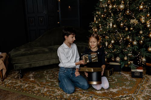 Children Exchanging Gifts by the Christmas Tree