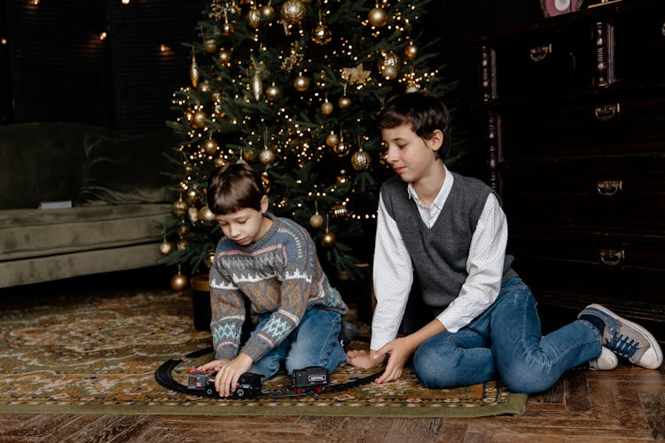 Boys Playing With A Toy Train Under A Christmas Tree