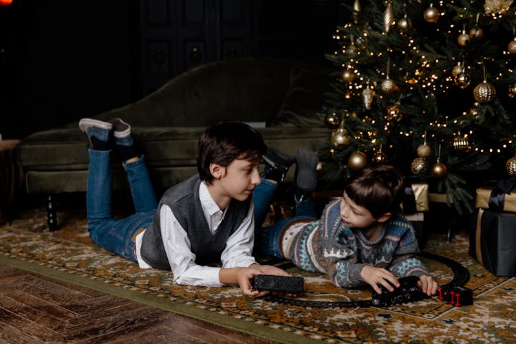 Brothers Playing With A Toy Train Under The Christmas Tree