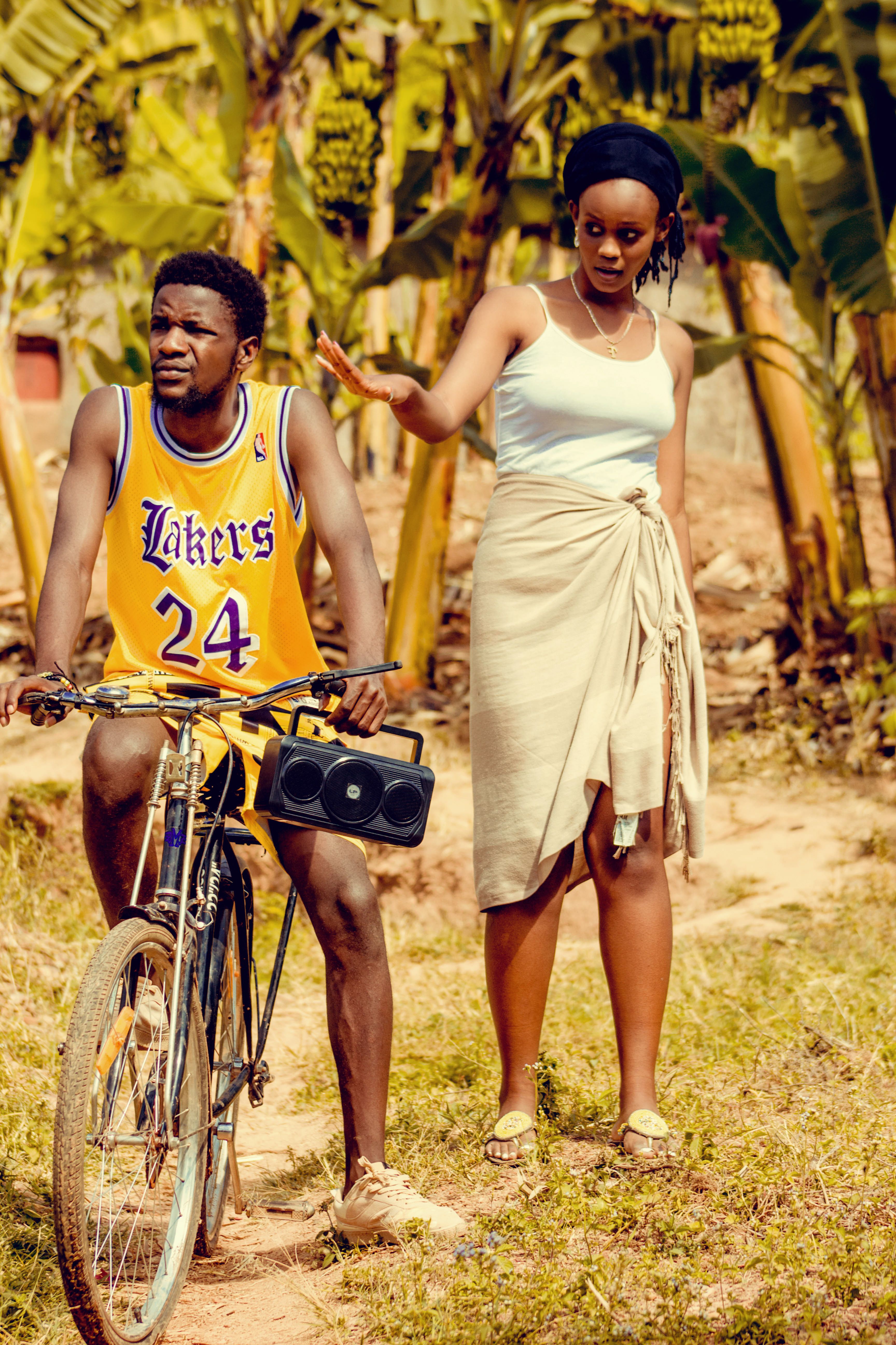 A young couple shares a moment outdoors with bicycle in sunlit Kigali, Rwanda.