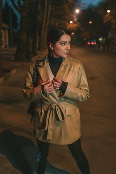A young woman poses confidently on a city street wearing a leather coat.