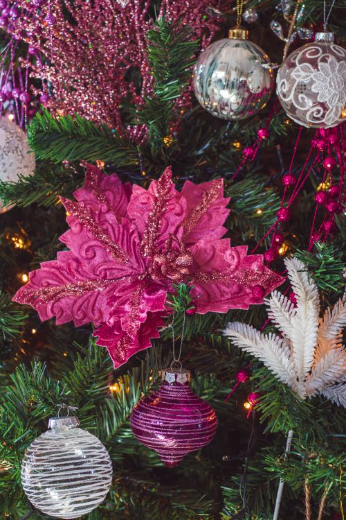 Free Close-up of festive Christmas tree adorned with pink baubles and floral decorations. Stock Photo