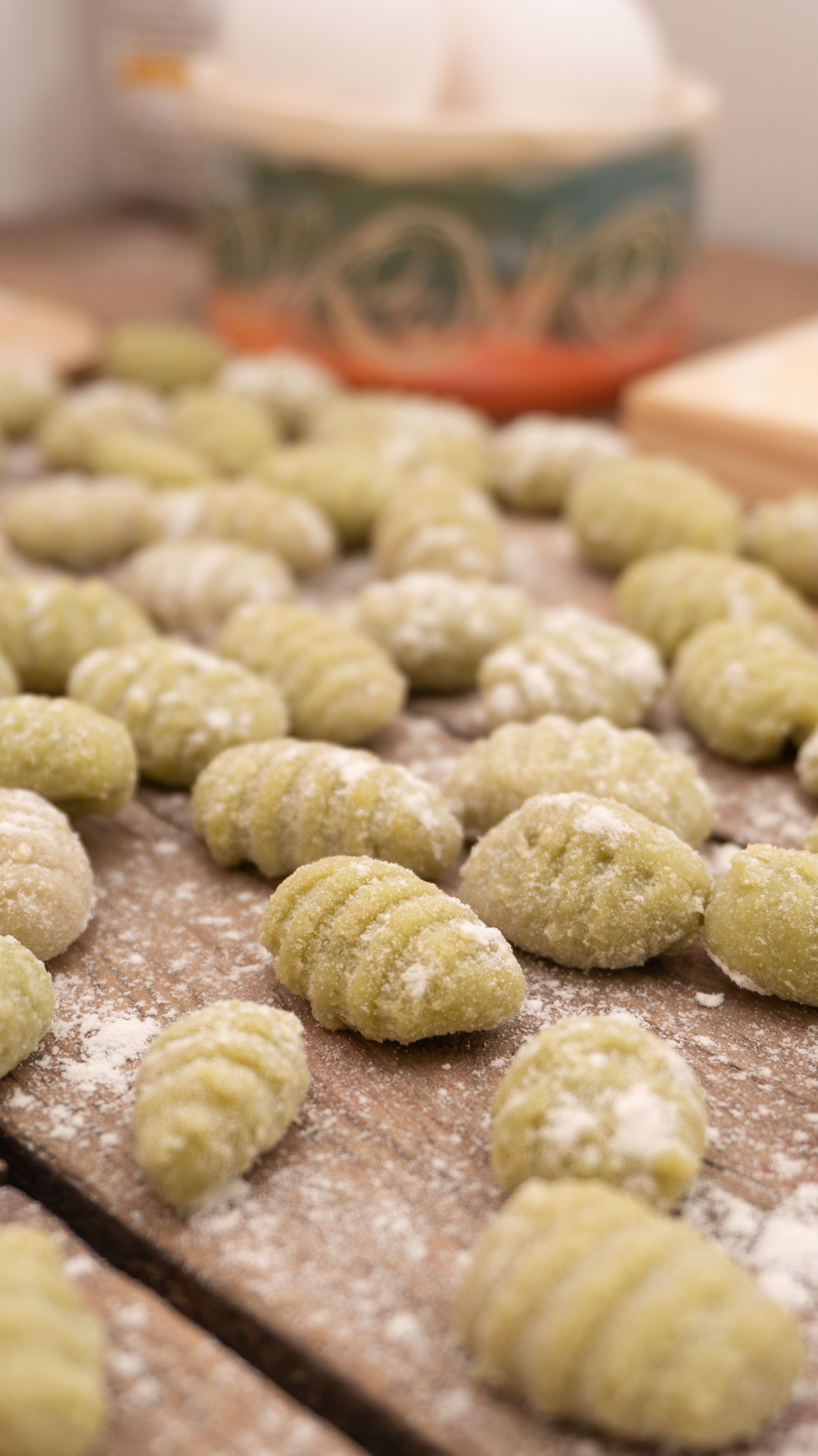 Fotomural Gnocchis de espinacas recién preparados descansando en una mesa de madera, espolvoreados con harina - un momento culinario artesanal perfecto.