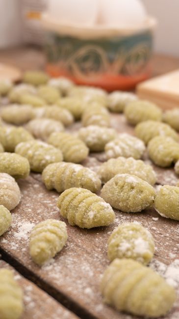 Fotomural Gnocchis de espinacas recién preparados descansando en una mesa de madera, espolvoreados con harina - un momento culinario artesanal perfecto.