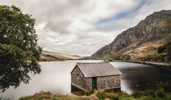 Charming stone boathouse by a tranquil lake with stunning mountain backdrop in Wales.