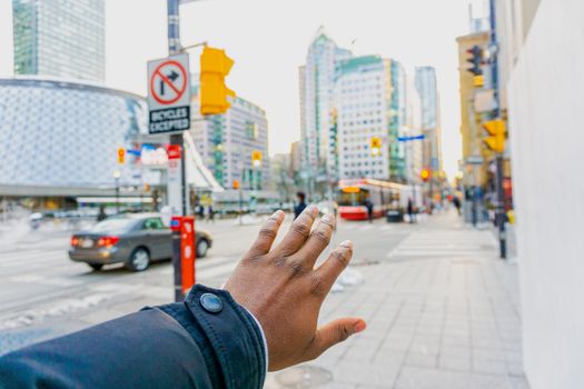 An outstretched hand against the backdrop of a vibrant Toronto street, capturing city life.