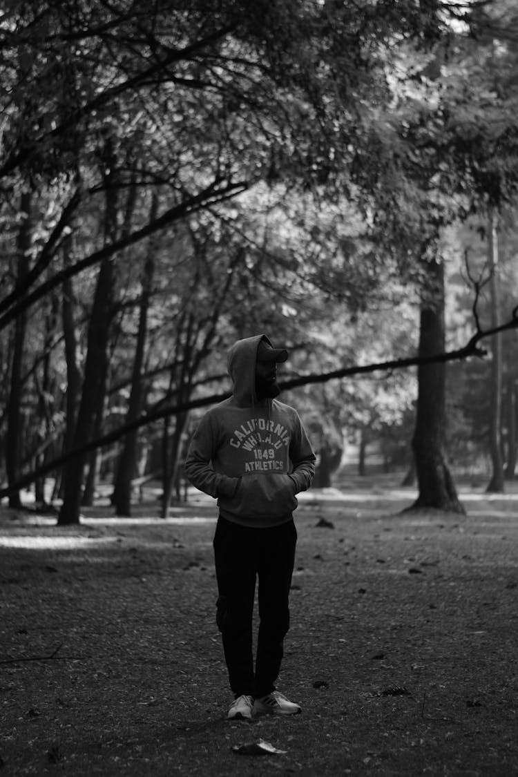 Grayscale Photography Of A Man In Hoodie Walking In The Forest