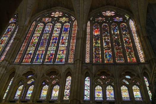 Intricate stained glass windows inside León Cathedral, Spain, showcasing vibrant colors and gothic architecture.
