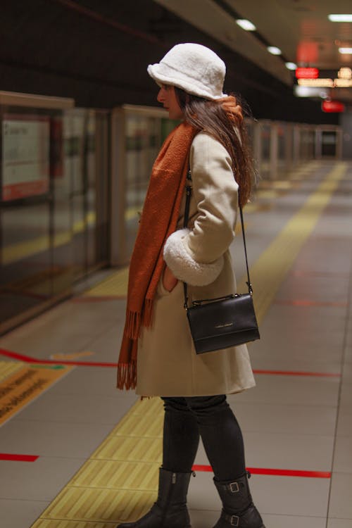 A woman in a hat and coat standing at a train station