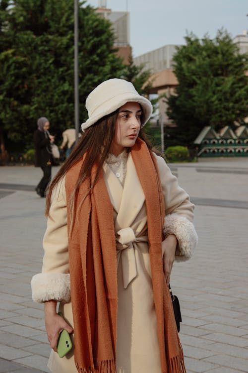 A woman in a long orange coat and hat