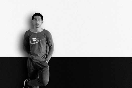 Stunning black and white portrait of a man standing against a two-tone background in casual attire.