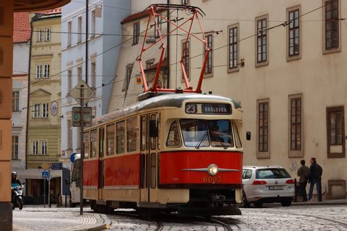 Free Classic red tram moves through a charming street in Prague, showcasing historic city architecture. Stock Photo