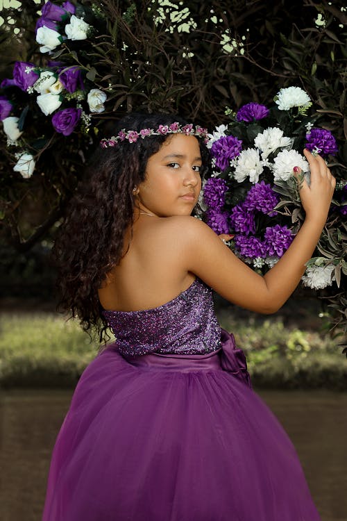 Cute Girl in Violet Dress Standing Near White and Violet Flowers