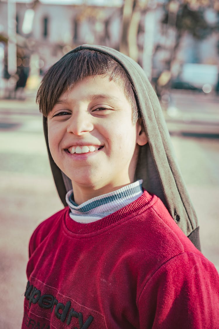 Smiling Boy With A Sweater Hanging On His Head 