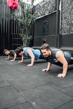 Three adult men doing push-ups outdoors in Mexico City gym.