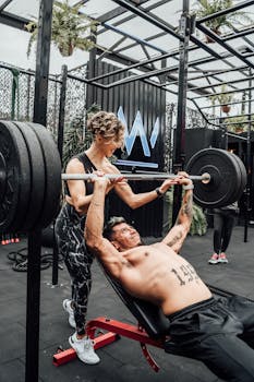 Muscular man and woman weightlifting at a modern Mexico City gym.