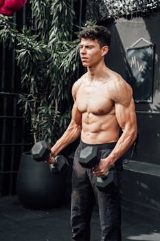 Muscular man exercising with dumbbells outdoors in Mexico City gym.