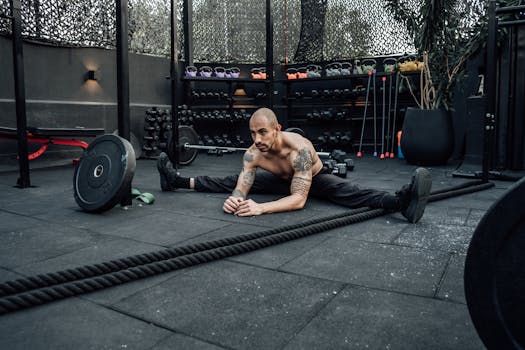 A shirtless man stretches in a modern indoor gym in Mexico City, showcasing fitness and determination.