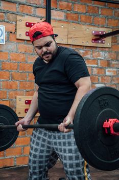 A man in a red cap lifts weights in a Mexico City gym, showing strength and determination.