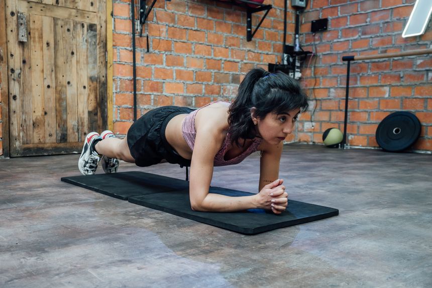 Athlete holding a plank in a brick-walled gym — photo by Miguel Gonzalez on Pexels