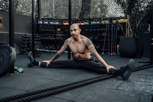 Tattooed man performing a split stretch in a gym, showcasing flexibility and fitness lifestyle in Mexico City.
