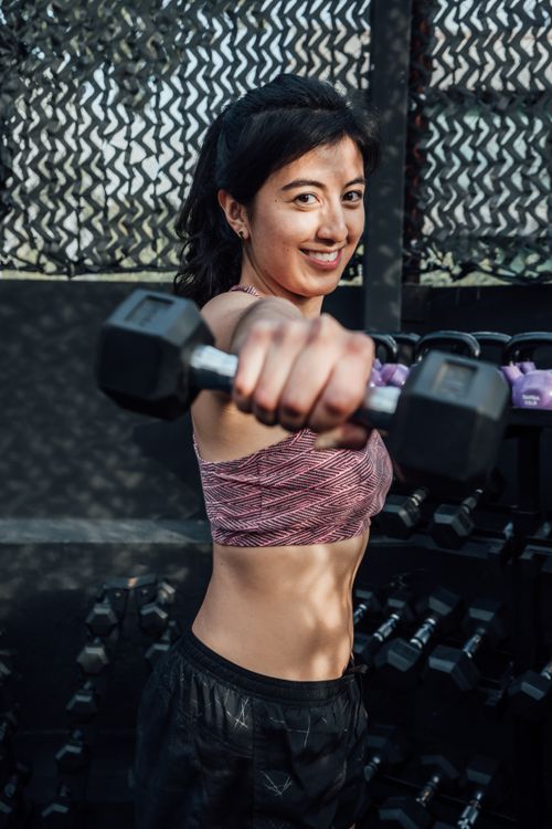 Free Fit woman lifting a dumbbell in a Mexico City gym, showcasing strength and confidence. Stock Photo