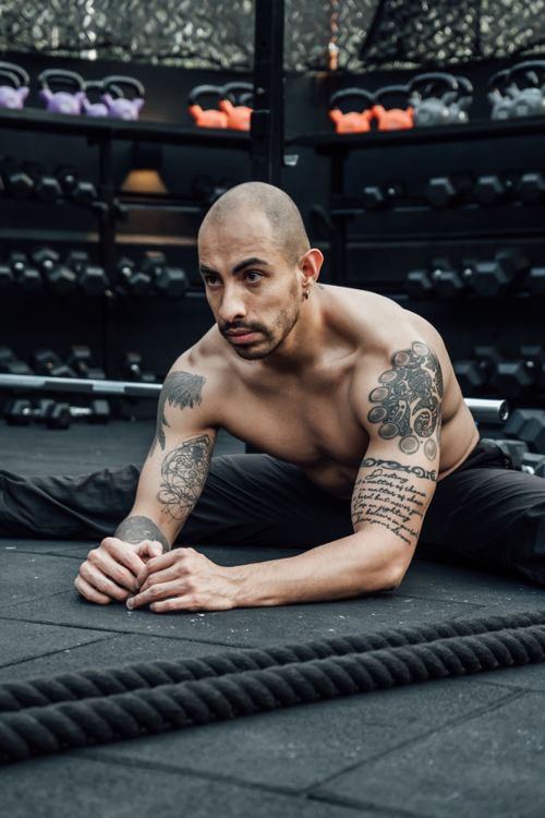Free Tattooed man doing a stretching exercise in an indoor gym in Mexico City. Stock Photo