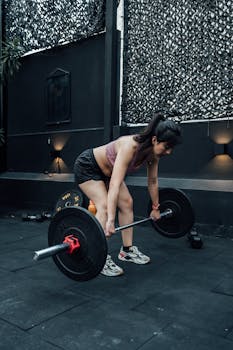A woman engaged in weightlifting with a barbell inside a Mexico City gym, showcasing strength and fitness.