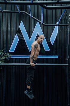Muscular man training shirtless indoors with neon lights in Mexico City gym.