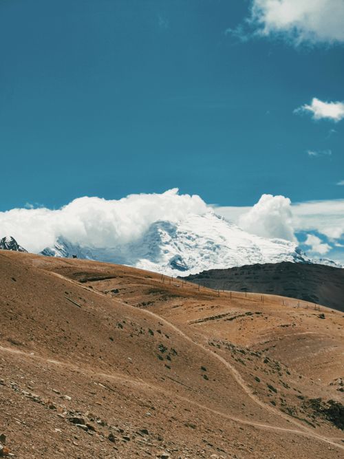 Free Scenic view of a snow-capped mountain with an arid landscape under a bright blue sky. Stock Photo
