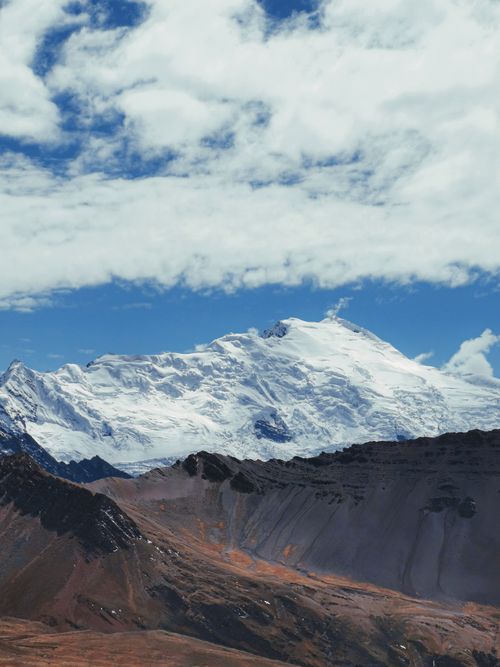 Free Stunning view of a snow-covered mountain peak under a bright blue sky with scattered clouds. Stock Photo