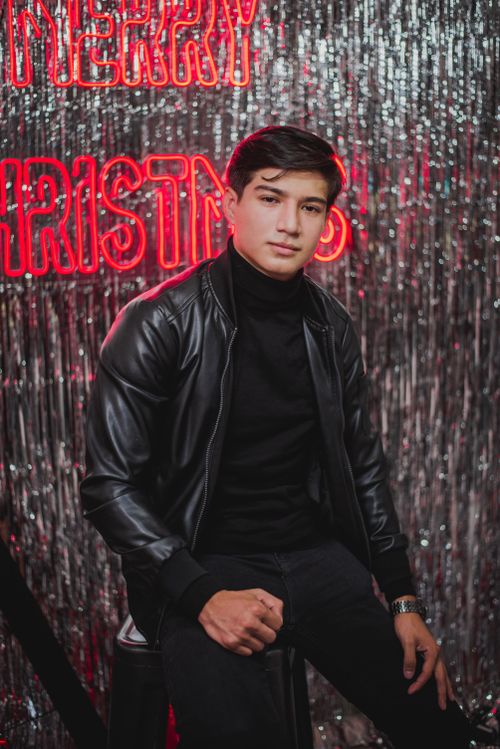 Free Stylish young man posing against a glittery Christmas backdrop. Perfect for holiday-themed projects. Stock Photo