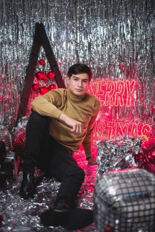 Free Young man posing in a Christmas-themed studio with neon lights. Stock Photo