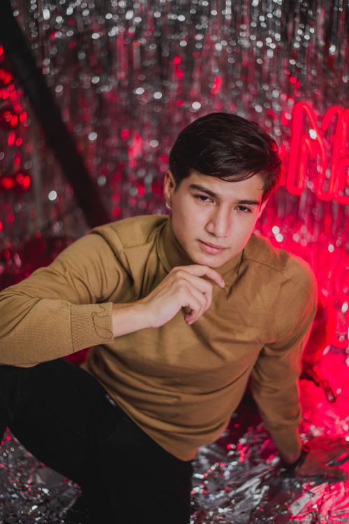 Free Young man posing with red neon lights and tinsel background, showcasing modern fashion. Stock Photo