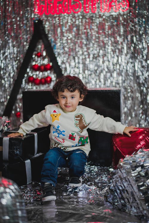 A Little Boy Sitting beside Christmas Gifts
