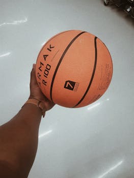 一只手握着室内的橙色篮球，纹理和细节清晰可见