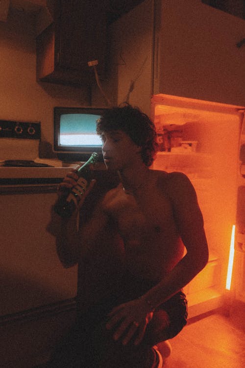 A Shirtless Man Drinking Soda