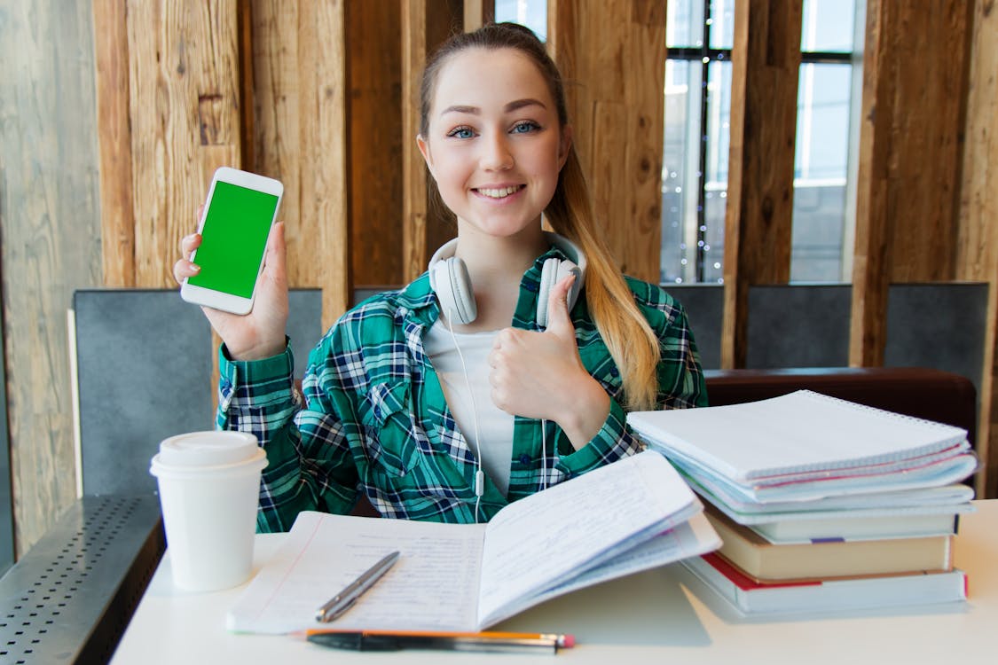 Free Smiling Woman Holding White Android Smartphone While Sitting Front of Table Stock Photo