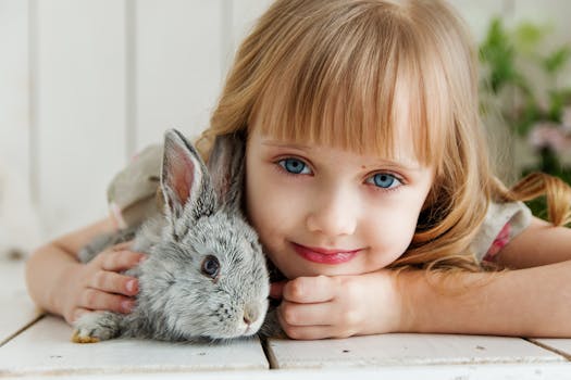 girl lying on white surface petting gray rabbit