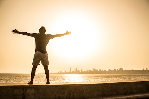 Free Man Standing on Ledge While Spreading Arms Stock Photo