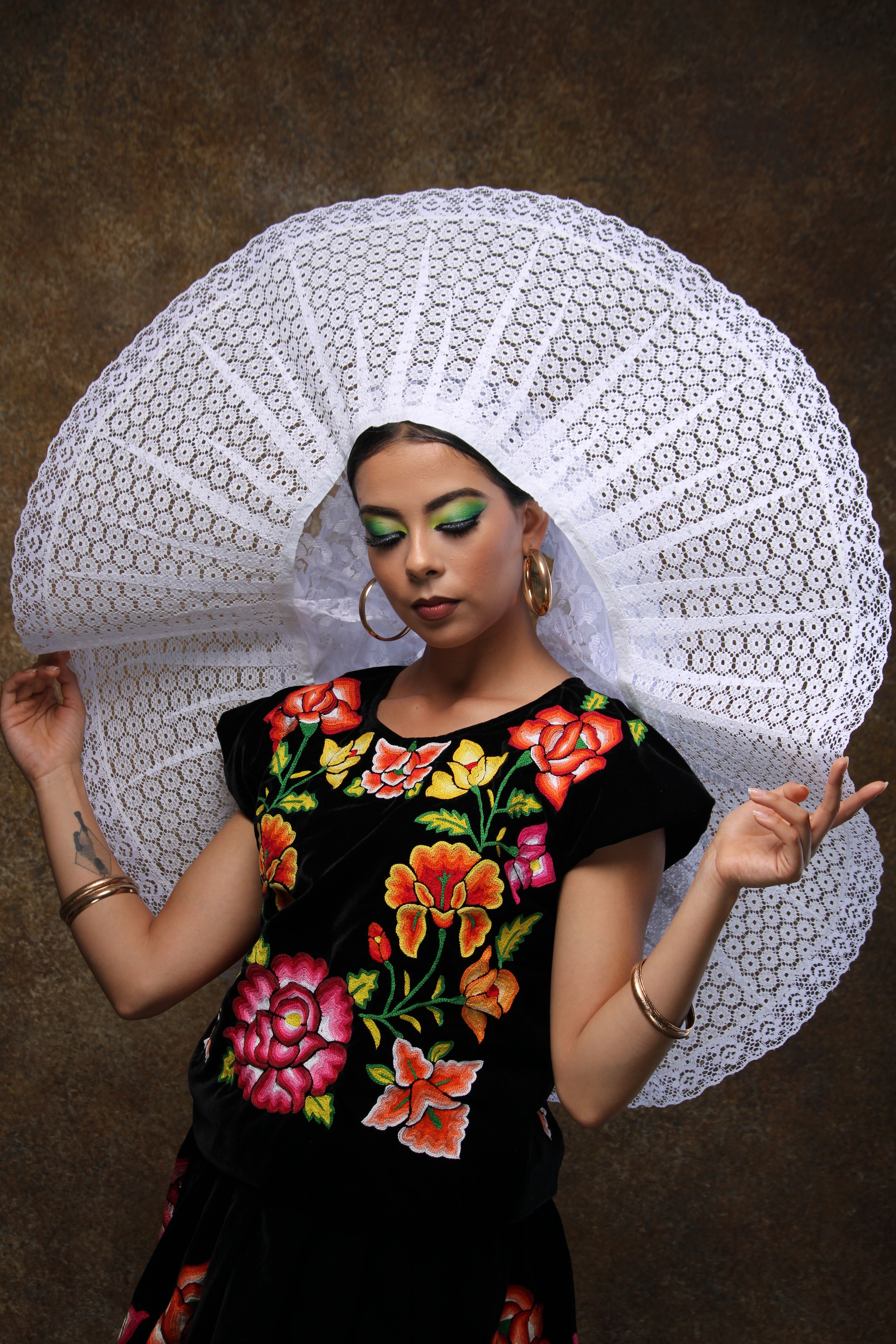 Portrait of a woman wearing vibrant traditional clothing with a large lace hat.