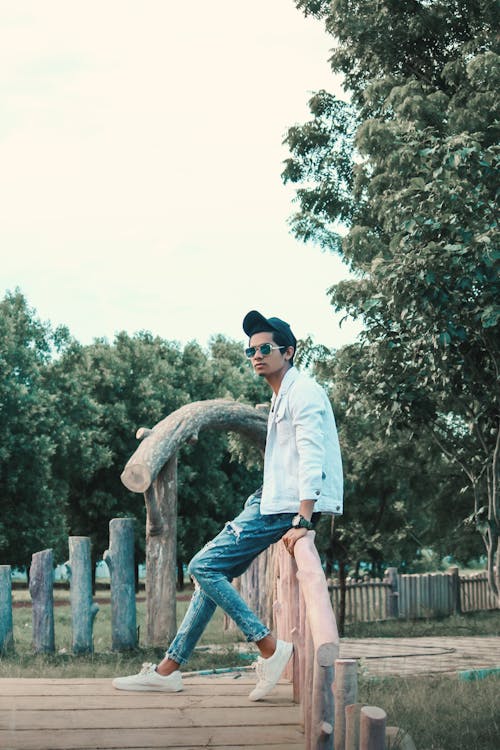 Young Man Sitting On A Wooden Bridge In A Park